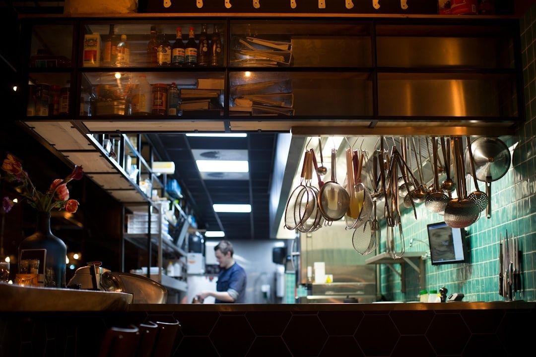 Restaurangkök med upphängda redskap och en arbetande kock