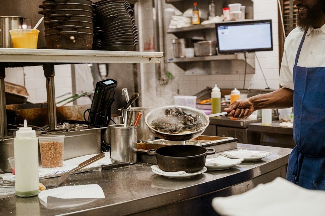 Köksmedarbetare håller upp en skål med råa räkor i restaurangköket